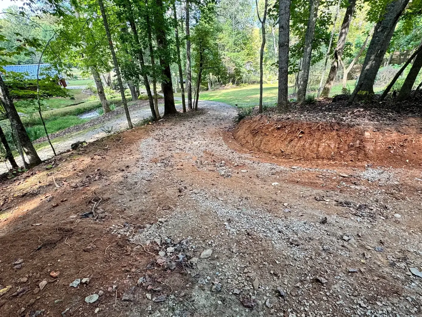 Narrow driveway turn widened by cutting back the bank, with fresh gravel surface